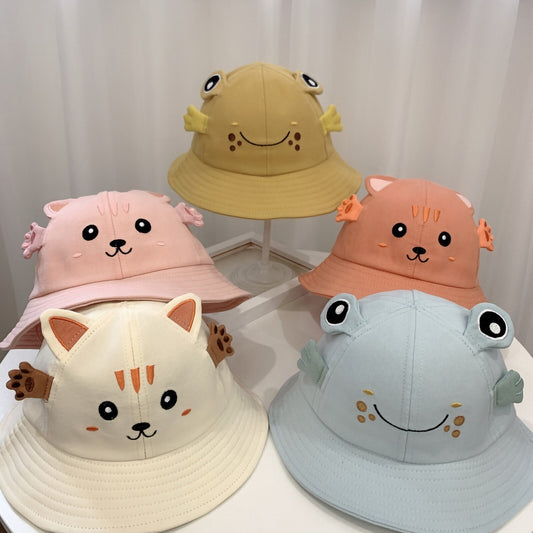Five cartoon-themed bucket hats on a white surface with a light gray curtain background.
